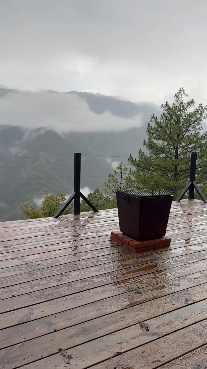 Terraza mojada por la lluvia con las montañas entre nubes.