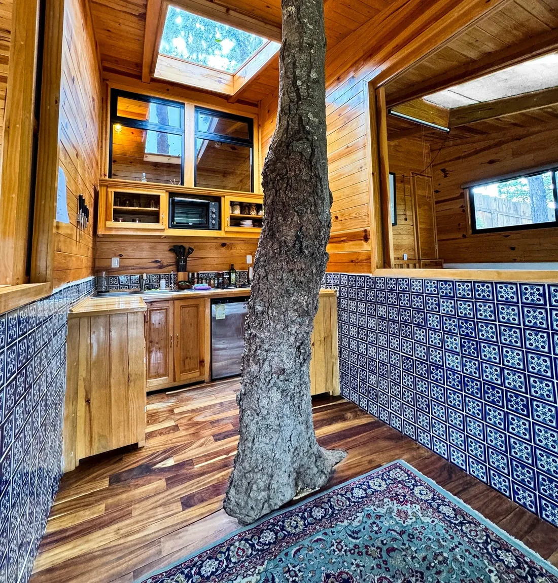 Interior de la Casa del Árbol con un tronco que atraviesa la cocina.