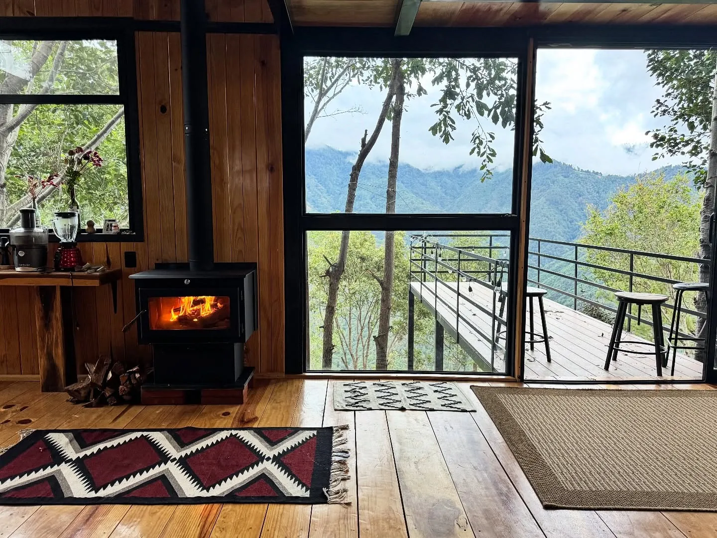 Casa Tierra: sala de cristal con estufa de leña y terraza a la sierra.